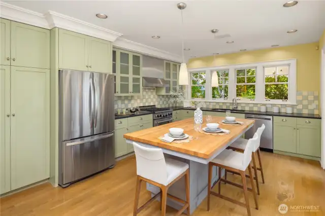 Custom cabinetry with incredible wooden pull-outs, a butcher block island, and high-end stainless appliances make this kitchen both beautiful and highly functional.
