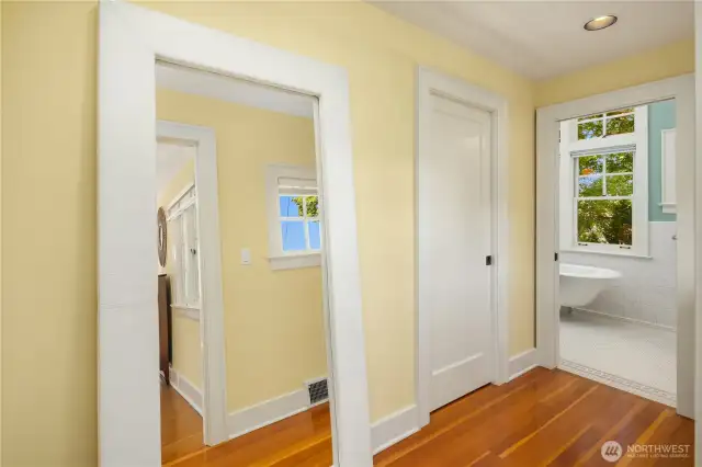 In the primary suite hallway, a walk-in closet sits opposite the entry to the light-filled upstairs bath.