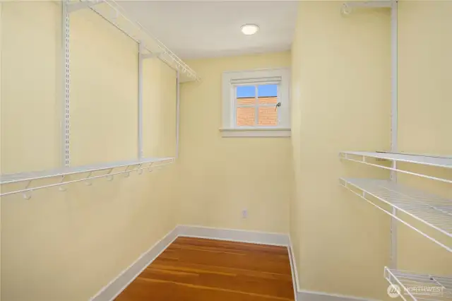 Spacious primary walk-in closet with built-in shelving and hanging space.