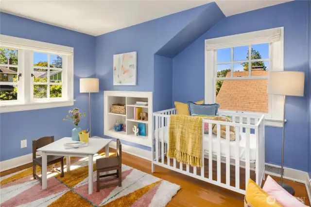 One of two additional upstairs bedrooms, featuring sunny windows and charming built-in bookshelves.
