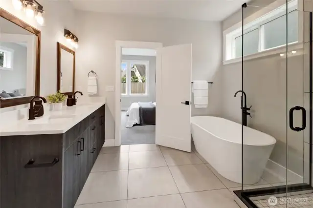 The primary bathroom features large-format ceramic tile, a generous soaker tub, and a double sink vanity—proof that the builder didn’t cut any corners when it came to luxury and quality.