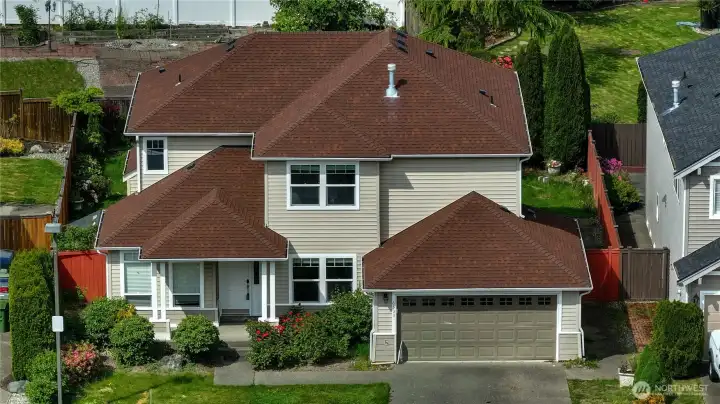 Situated in a well-kept neighborhood, the property features a functional layout with a large two-car garage, inviting covered front porch, and mature greenery throughout the lot.