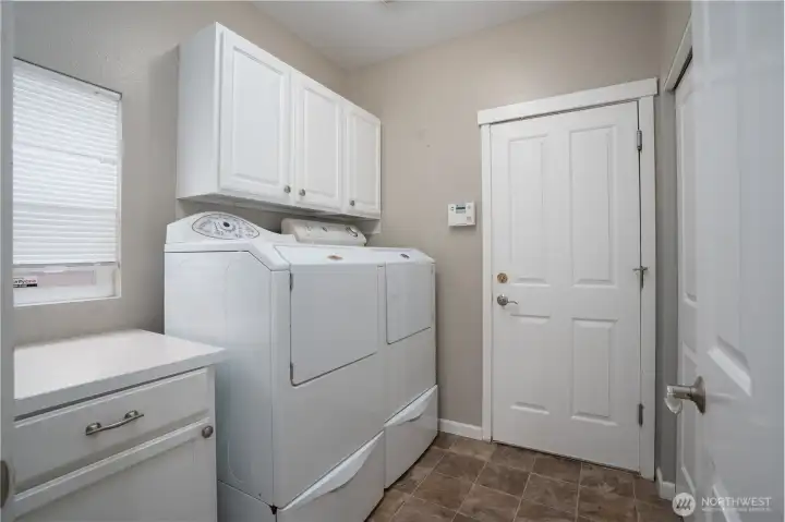 Spacious laundry room with built-in cabinetry, extra counter space, and direct outdoor access—designed for convenience, storage, and everyday functionality.
