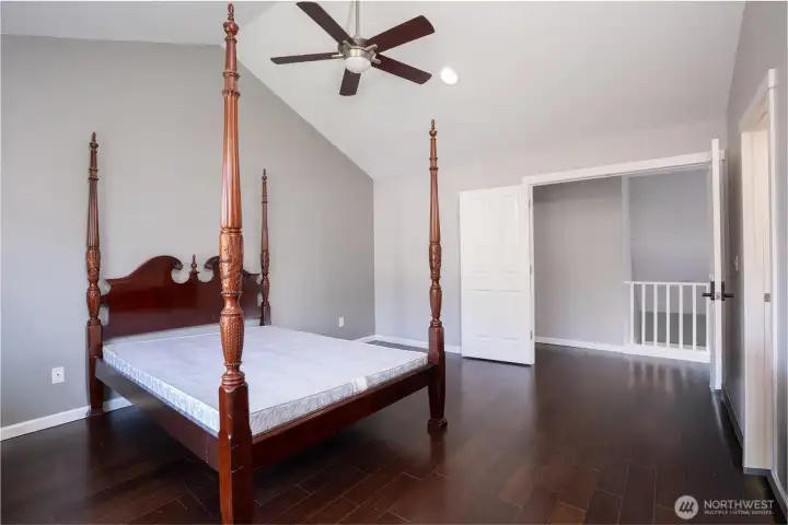 Spacious primary suite with vaulted ceilings, rich flooring, and plenty of room for a full bedroom setup and additional seating or retreat space.