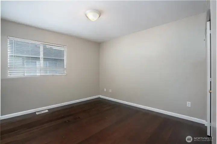Comfortable secondary bedroom with rich flooring, natural light, and flexible space for guests, a home office, or everyday living.
