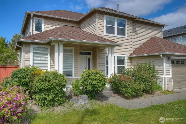 Inviting front exterior with mature landscaping, colorful flowers, and charming curb appeal that creates a warm welcome home.
