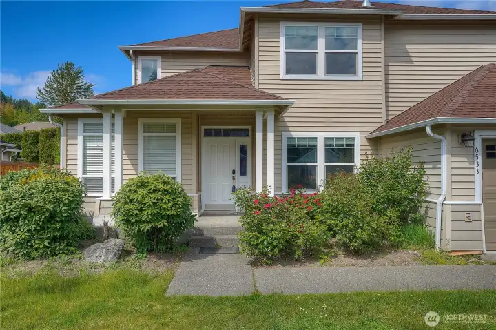 Charming front entry with covered porch, mature landscaping, and inviting curb appeal.
