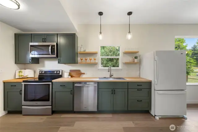 Kitchen features durable butcher block counters that blend style & practicality in a clean, modern layout