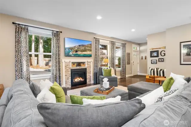 From this side of the living room, the details shine. A wall of windows brightens the space while the gas fireplace anchors it with modern tile and a minimalist inset shelf ready for a favorite piece or the big game. The sightline to the entry adds that open-concept ease without losing definition.