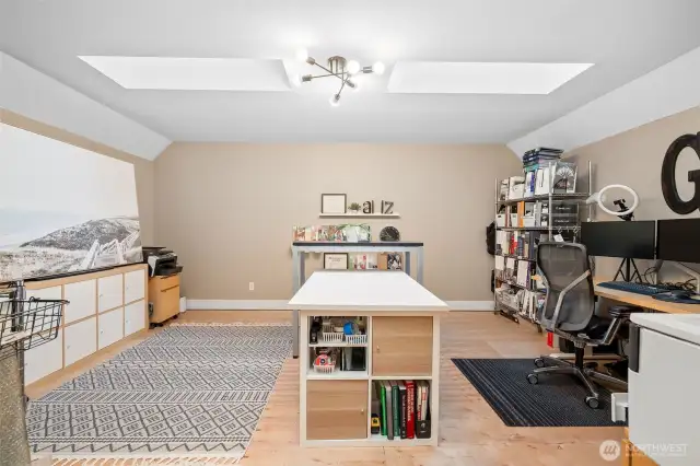 This upper bonus room doubles as a chic den or extra sleeping space, thanks to its bright vibe and unique details. Two skylights flood the room with natural light, while the eye-catching Sputnik light fixture adds mid-century flair. Light-toned flooring keeps the space feeling open and fresh.