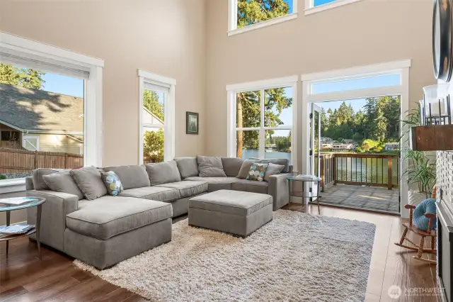 Unit B’s living room stuns with soaring two-story vaulted ceilings and walls of windows showcasing stunning lake views. Glass French doors open to a spacious upper balcony deck, perfect for taking it all in. A gas fireplace with a wood mantle adds cozy charm to this light-filled space that’s all about bright, airy living. A loft in the living room would make additional square footage with awesome lake views if a railing and ladder were added.