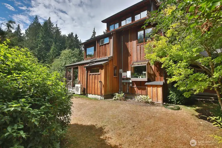 East side of the home. The garden window is at the kitchen sink. On demand water heater is to the left of the garden window and the solar battery is in the paneled box to the right of the window.
