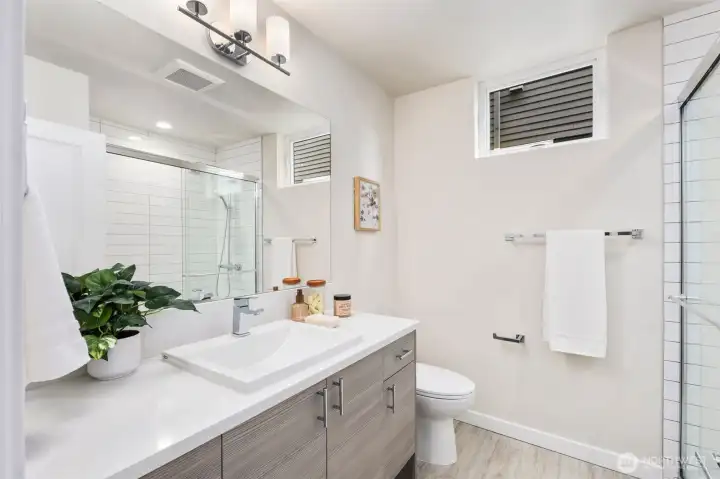Entry level 3/4 bathroom allows natural light, custom cabinetry, and tiled showers and floors.  There is no vinyl in this home!  The bathroom on this level next to the extra large bedroom allows for guests to enjoy their own private retreat.