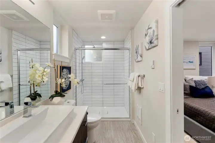 Primary ensuite bathroom with featured trough sink, walk in tiled shower, and built in shelving.  Picture of the clay color scheme of a previous model home.