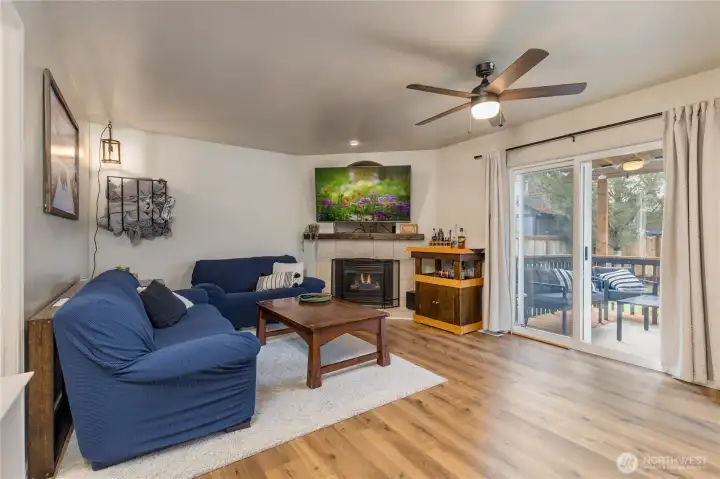 Family room features a cozy corner gas fireplace and slider to the covered deck