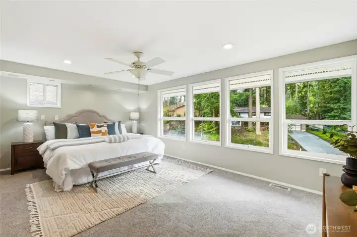 Spacious Primary Bedroom with Large Windows and Peaceful Forest Park Setting
