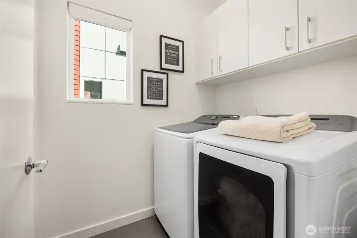 The laundry room has full size washer and dryer and custom cabinets for storage.