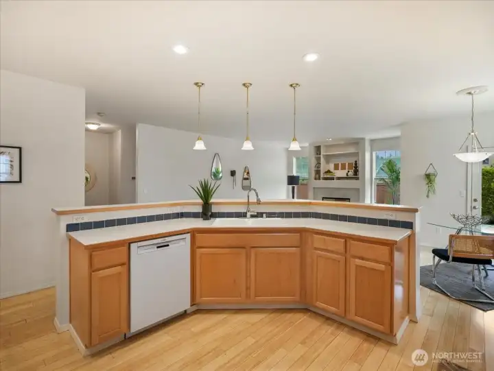 Bright kitchen with warm maple cabinets stainless sink, and generous counter space accented by pendant lighting above the eating bar.