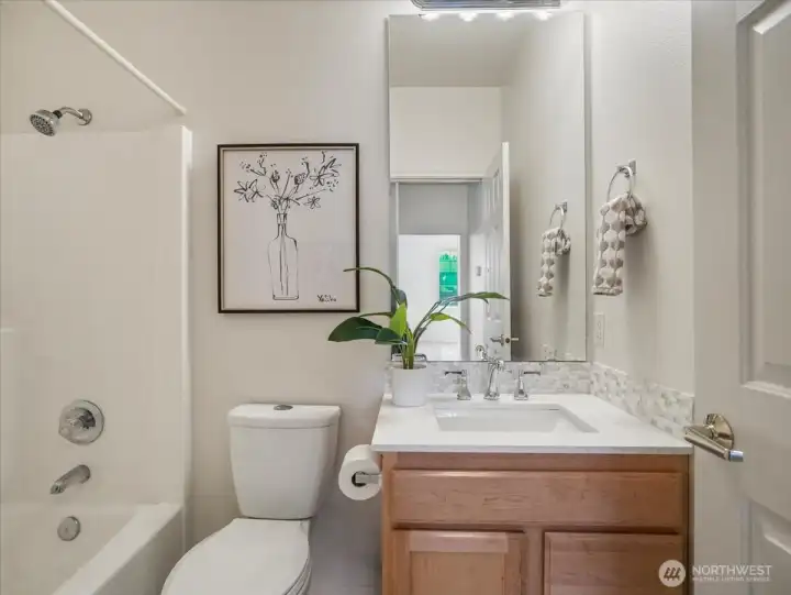 Full guest bathroom enhanced with a new quartz countertop, sleek faucet and tasteful tile backsplash.