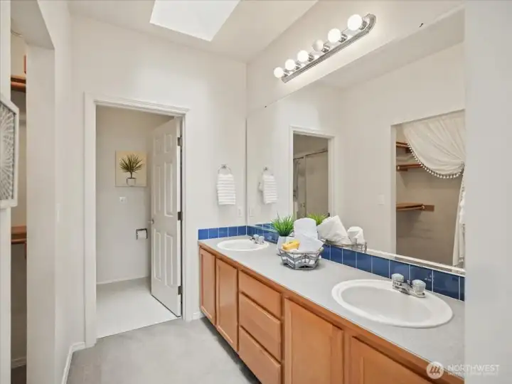 Spacious 3/4 primary bathroom with dual vanities, private toilet space, walk-in shower and linen closet.
