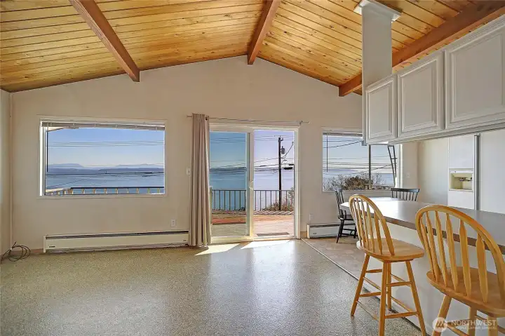 Open living space with vaulted wood ceilings and large windows capturing natural light and water views.