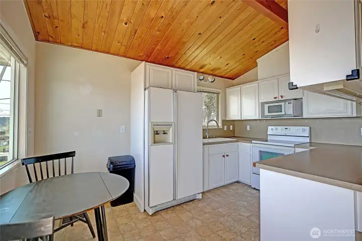 Bright kitchen with vaulted wood ceilings and an efficient layout, open to the dining area.