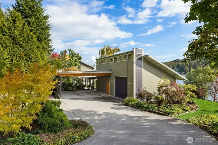 A paved driveway leads to the 2-vehicle carport, one-car garage, and overflow parking.