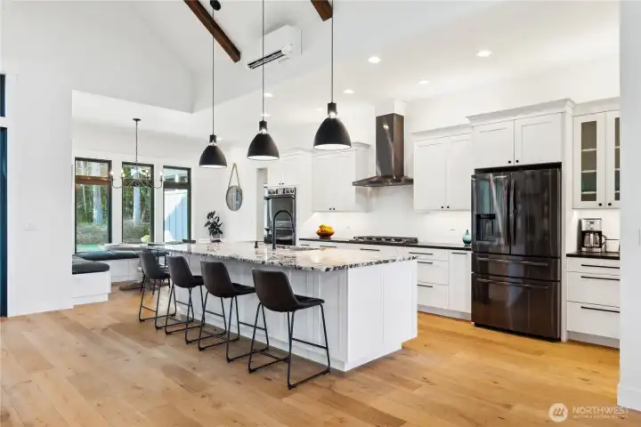 Stunning kitchen with granite counters, double oven, island with eating space, coffee station, wood floors and soaring ceilings.