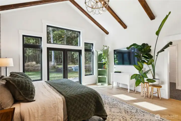 Walls of windows flood the primary suite with warmth and light overlooking the private, pristine backyard. It offers vaulted, beamed ceiling and wood floors.