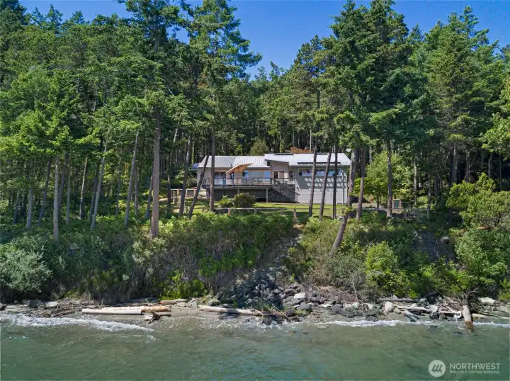 Private San Juan Island waterfront retreat nestled among mature evergreens with shoreline just below, offering a peaceful island setting and direct connection to the natural beauty of the Salish Sea.