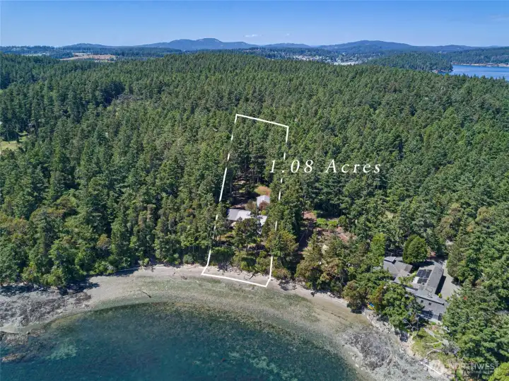 Aerial view of the 1+ acre waterfront property showcasing its private forested setting, beach frontage, and proximity to Friday Harbor, Turn Island, and surrounding San Juan Island scenery.