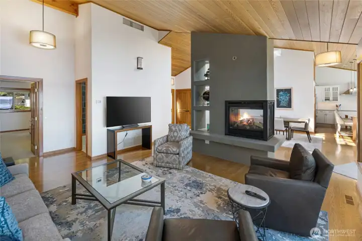 Main living area features a statement fireplace, hardwood floors, open sightlines to the dining and kitchen areas, and a thoughtful layout designed for relaxed waterfront living.