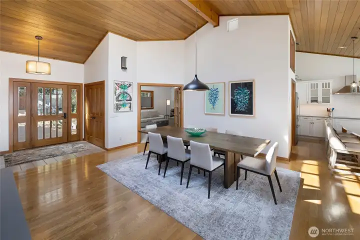 Spacious dining area with vaulted ceilings, hardwood floors, natural wood trim, and an open connection to the kitchen and living spaces, creating an inviting layout for island living.
