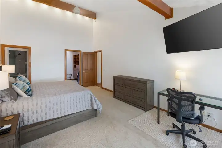Spacious primary bedroom includes room for a work-from-home setup, private bath access, ample storage, and a comfortable layout with nearby waterfront deck access.