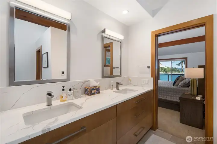 Updated primary bath features dual sinks, quartz-style counters, modern cabinetry, and a clean, refreshed design connected to the waterfront primary suite.