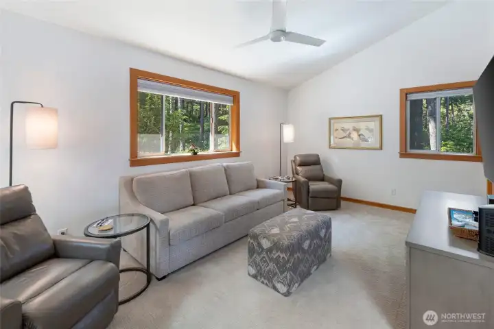 Comfortable den or flex room with large windows overlooking the surrounding evergreens, offering space for guests, media, reading, or a home office.