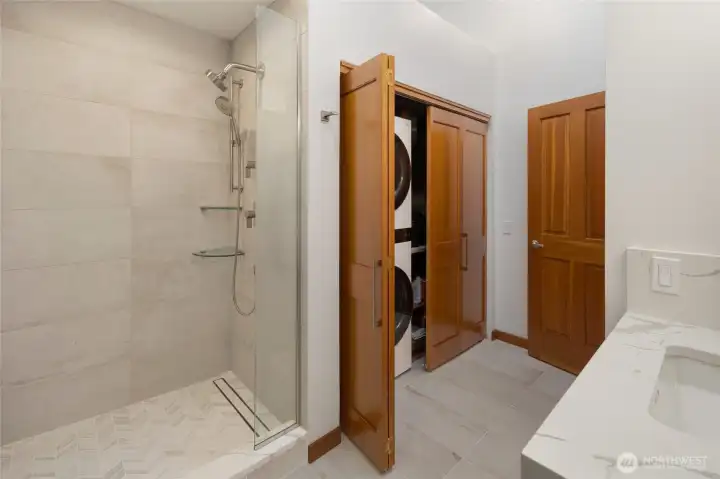 Thoughtfully designed bath and laundry area with glass-enclosed shower, updated tilework, built-in laundry storage, and modern finishes for everyday island living.