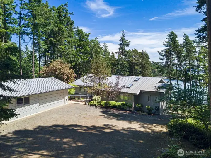 Private driveway approach showcases the detached garage, main residence, mature landscaping, and peaceful forested setting near the San Juan Island shoreline.