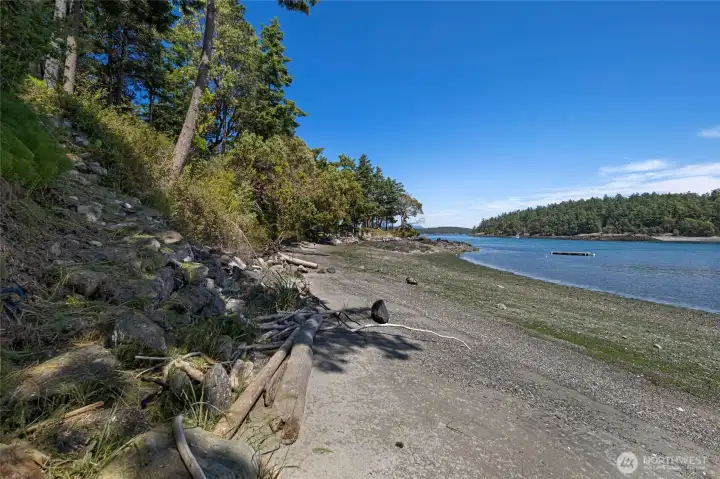 Natural beach frontage with driftwood, rocky shoreline, and calm water access offers a quintessential San Juan Island waterfront experience.