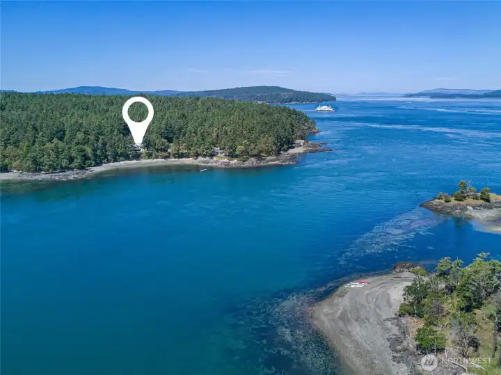 Aerial view highlights the home’s scenic position along a protected cove with nearby island views, turquoise water, and easy access to shoreline recreation.