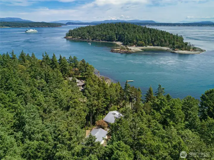 Aerial perspective captures the private forested waterfront setting, with the home nestled among mature evergreens near Friday Harbor and nearby island channels.
