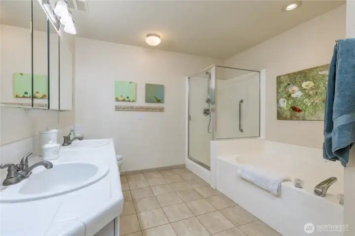 Spa-like 5-piece primary bathroom boasts a large soaking tub, dual sinks, and durable tile floors.