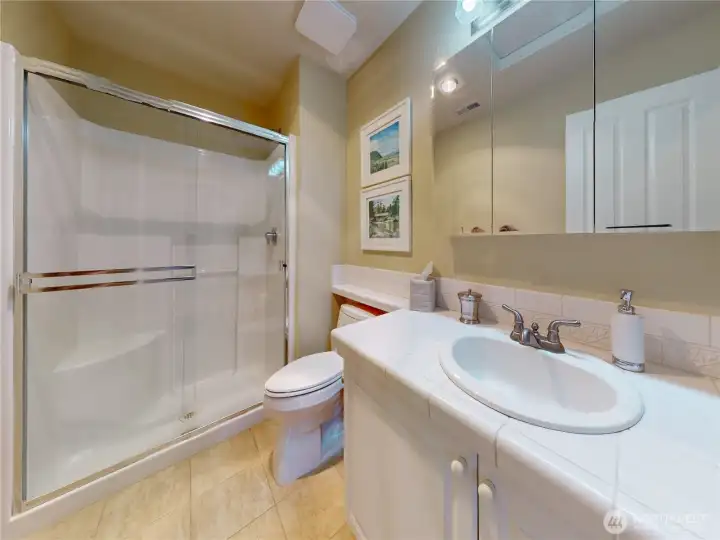Upstairs hallway 3/4 bath featuring tile flooring and a glass-enclosed shower.