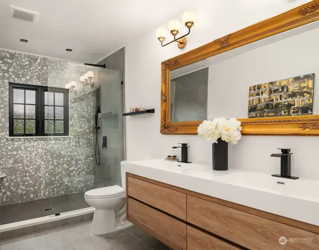 The en-suite bathroom boasts a spa-like rain shower, Italian Terrazzo tile, and a modern vanity with designer sconces.