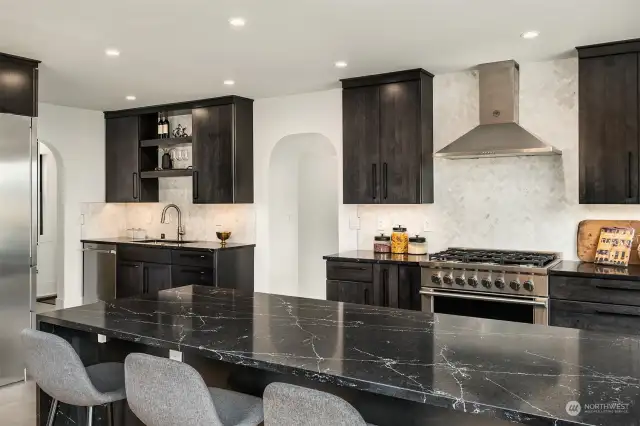 A chef's kitchen with a stunning waterfall quartz island, high-end appliances from Libher and Fisher & Paykel, and Kohler fixtures.