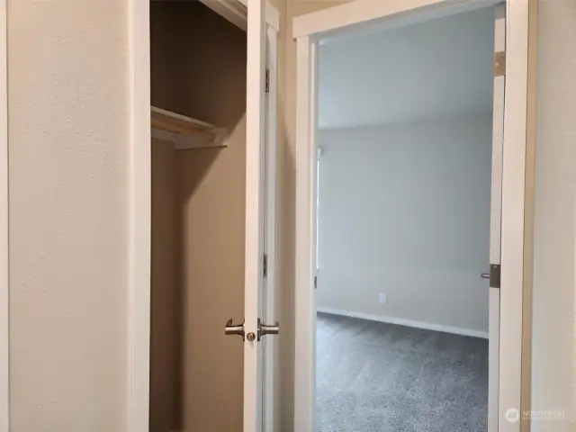 side hallway with linen closet and view to Bedroom #1.