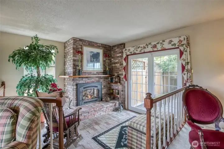 Front room with a propane fireplace for conversation or reading, also a door out to a large wooden deck.