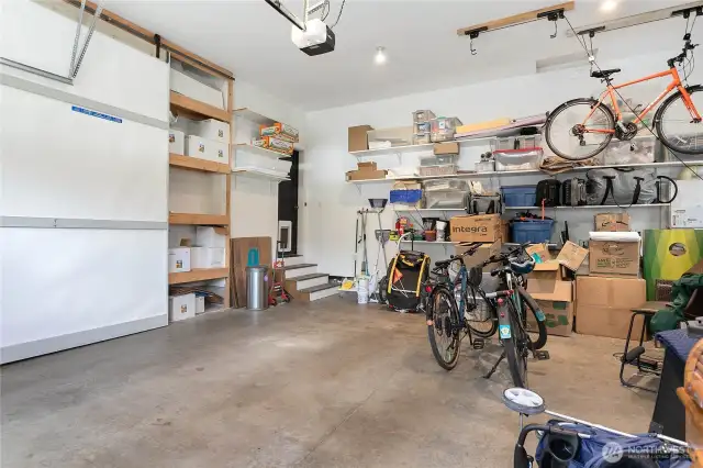 Impressively large two-car garage with a soaring ceiling and custom built-in shelving behind sliding barndoors.