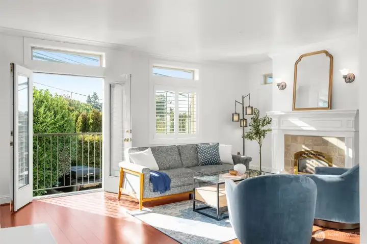 Generous living room with great western natural light, gas fireplace, wood floors, and Juliette balcony