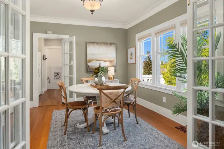 The dining room shines with classic French doors, rich wood floors, and tree-lined views - an ideal spot for intimate dinners or lively gatherings.